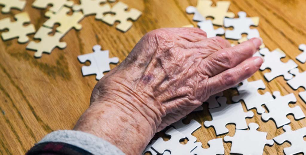 Ældre person løser puslespil for at holde hjernen aktiv og mindske demensrisiko.